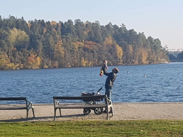 스웨덴 스톡홀름의 호숫가에서 한 남성이 아이를 돌보고 있다.