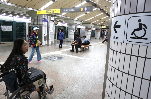 기자가 휠체어를 이용해 5호선 종로3가 역에 내려 승강장에 붙어있는 휠체어리프트 안내표지판을 확인하고 있다. ⓒ이정실 여성신문 사진기자