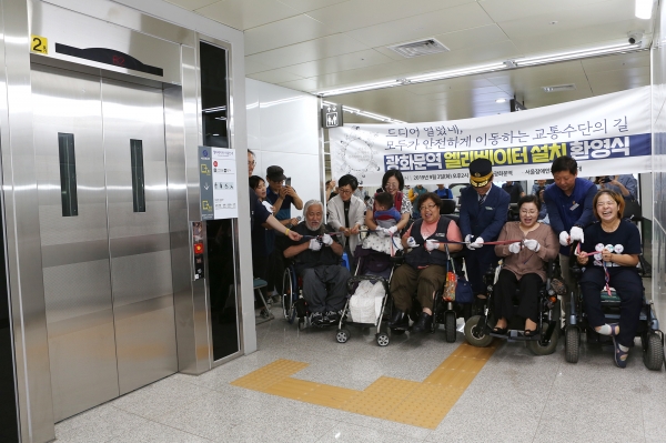 서울장애인차별철폐연대 회원들이 광화문역 엘리베이터 완공 축하하며 테이프 커팅식을 하고 있다.