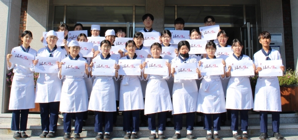 제과제빵 1반 학생들이 히포시캠페인에 참여하고 사인지를 펼쳐보이고 있다.