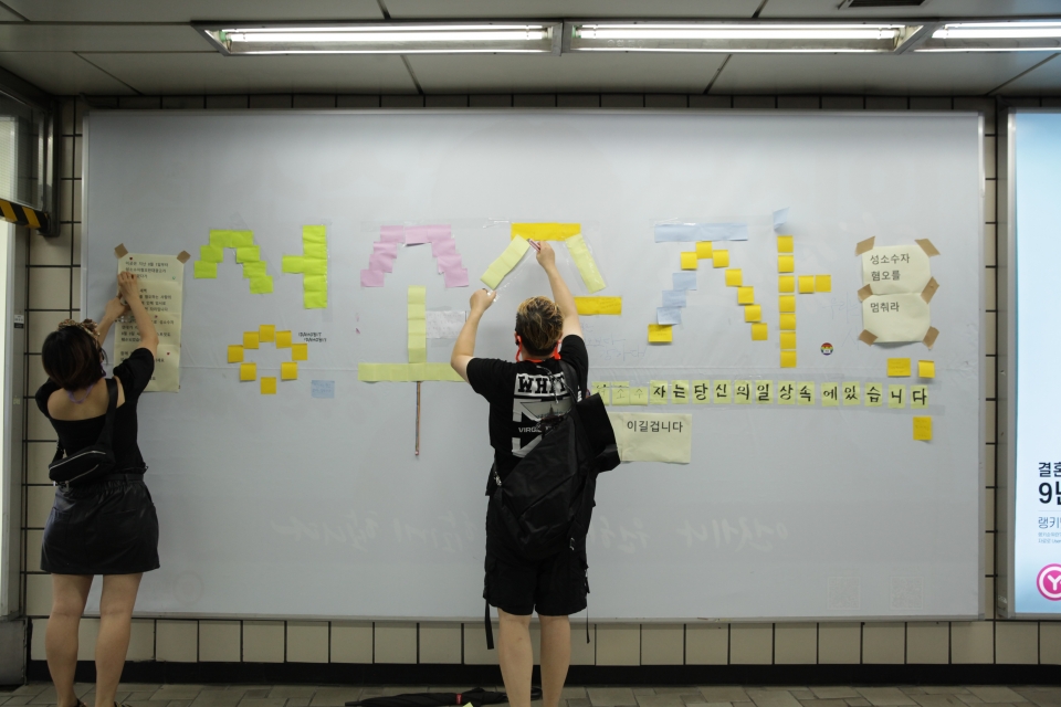 지난 8월 3일 오후 서울 마포구 신촌역에 게시됐던 성소수자 차별 반대 광고판이 훼손되자 시민들이 포스트잇으로 '성소수자'라는 글자를 복구하고 있다.