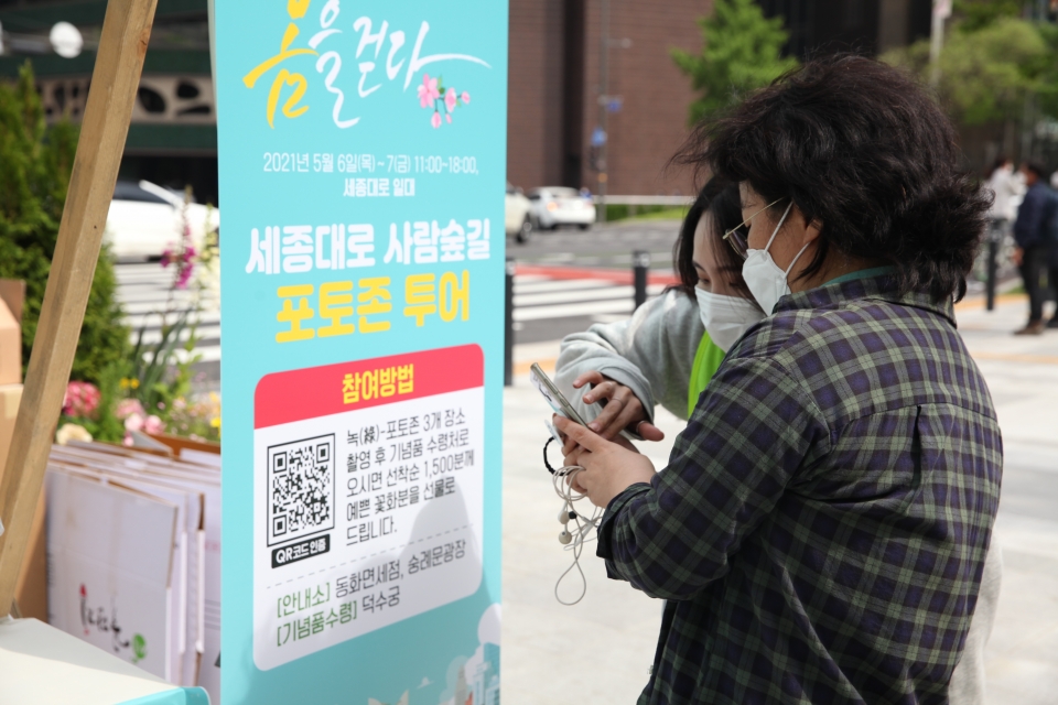 7일 서울 중구 세종대로 사람숲길 행사에서 한 시민은 포토 이벤트 참여하여 방법 설명을 듣고 있다. ⓒ홍수형 기자