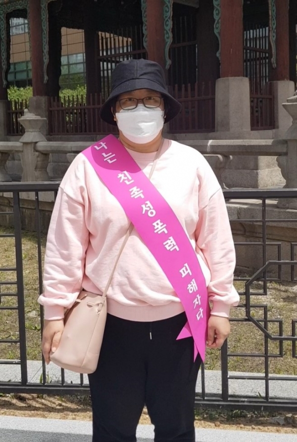 친족성폭력 생존자 ‘명아’는 5월8일 광화문 시위에서 ‘나는 친족성폭력 피해자다’ 어깨띠를 둘렀다. ⓒ여성신문