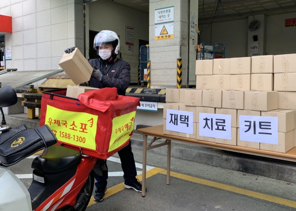 16일 대전 서구 둔산우체국에서 집배원이 코로나19 재택치료자들에게 배송할 재택치료키트 상자를 이륜차에 싣고 있다.  ⓒ우정사업본부 제공