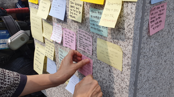 서이초등학교 앞 추모문화제에 참여한 한 교사가 사망한 20대 초등 교사를 애도하는 글귀를 적은 포스트잇을 붙이고 있다. ⓒ이수진 기자