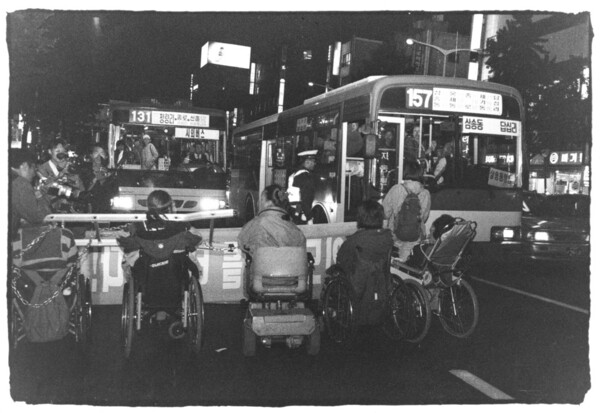 장애인이동권연대 소속 장애 활동가들이 2001년 10월 31일 서울 종로 거리에서 저상버스 도입 등 장애인 이동권 확보를 요구하며 사다리와 쇠사슬로 몸을 고정한 채 기습 점거 시위를 벌이고 있다. ⓒ장애인이동권연대