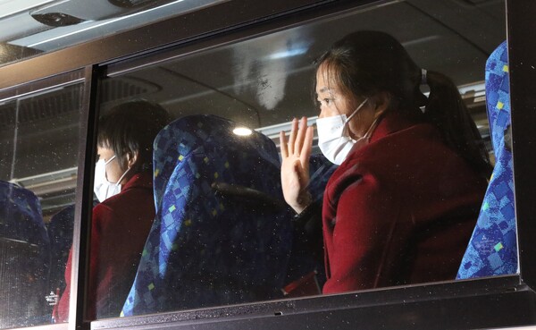 붉은색 코트를 입은 북한 여자축구 대표팀 선수가 25일 도쿄 하네다공항을 통해 일본에 입국한 뒤 버스에 올라 취재진을 향해 손을 흔들고 있다. ⓒ연합뉴스