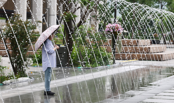 잠시 소나기가 내린 지난 8일 오후 서울 광화문광장에서 우산을 쓴 시민들이 분수대를 지나가고 있다.  ⓒ연합뉴스