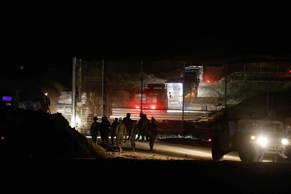 (가자시티 로이터=연합뉴스) 21일(현지시각) 이스라엘군이 가자 지구에서 경계를 서고 있는 가운데 인도주의 물자를 실은 구호 트럭이  국경으로 진입하고 있다.
