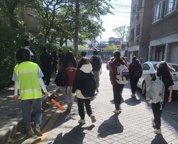연두색 조끼를 입은 모아센터 직원이 학생들의 안전을 위한 통학로 순찰 활동을 하고 있다. ⓒ성북구
