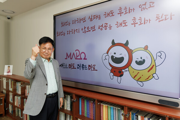 박강수 마포구청장이 여성신문과의 인터뷰 후 자신의 좌우명 문구 앞에서 포즈를 취하고 있다. (사진 = 마포구청)