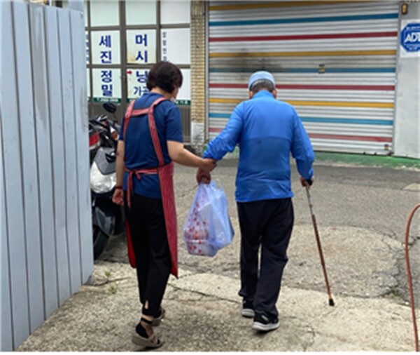 영등포구 문래동 자원봉사캠프에서 활동하는 한 봉사자가 복지사각지대 어르신에게 명절음식을 전달하고 동행하고 있다. ⓒ서울시자원봉사센터