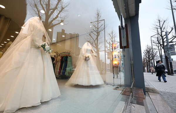 지난해 3월 19일 서울 마포구 아현동 웨딩거리에서 한 시민이 웨딩드레스 앞을 지나고 있다. ⓒ연합뉴스