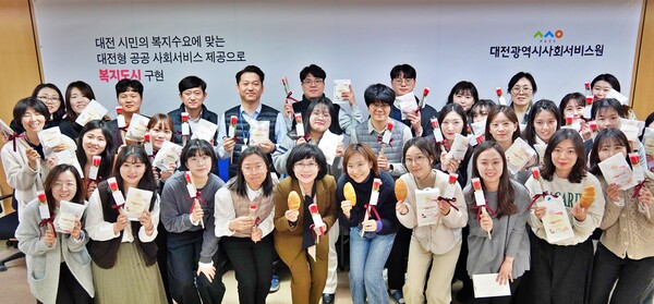 3.8 세계여성의 날을 맞아 대전사회서비스원 김인식 원장(왼쪽에서 다섯번째)과 직원들이 빵과 장미를 들고 기념촬영을 하고 있다. ⓒ대전시사회서비스원