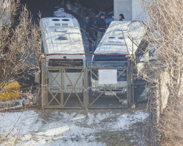 9일 오전 서울 용산구 한남동 대통령 관저에서 경호처 직원이 철조망이 쳐진 쪽문을 버스로 벽을 치고 있다. ⓒ연합뉴스