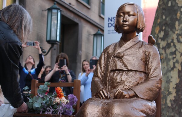 8일(현지시간) 독일 쾰른 나치기록박물관 앞에서 열린 평화의 소녀상 제막식에서 한 시민이 꽃다발 놓고 있다. ⓒ연합뉴스