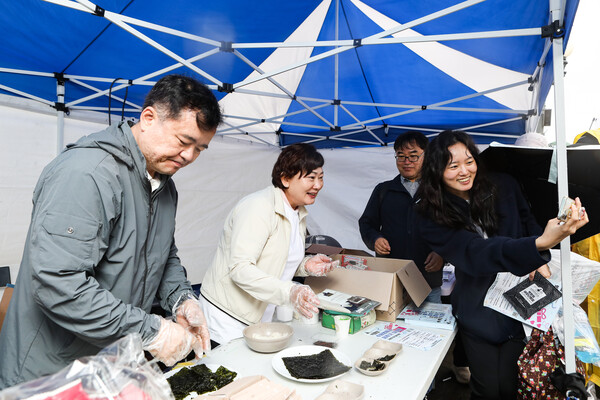 농업회사법인 (주)한백식품의 프리미엄 김 브랜드 박향희김이 3일 서울 마포구 상암 월드컵공원 평화광장에서 열린 ‘2025 여성마라톤 대회’에 참가했다. 박향희 대표(가운데)가 마라톤 대회 참가자에게 김을 나눠주며 사진 촬영을 하고 있다. ⓒ손상민 기자