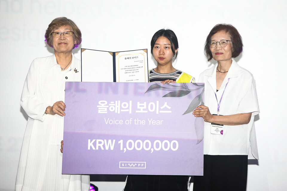 이지영 금속노조 한국옵티칼하이테크지회 사무장이 박정혜 수석부지회장과 소현숙 조직부장을 대리해 21일 저녁 7시 서울 서대문구 메가박스 신촌에서 열린 제27회 서울국제여성영화제 개막식에서 ‘올해의 보이스’ 상을 받고 있다. ⓒ손상민 사진기자