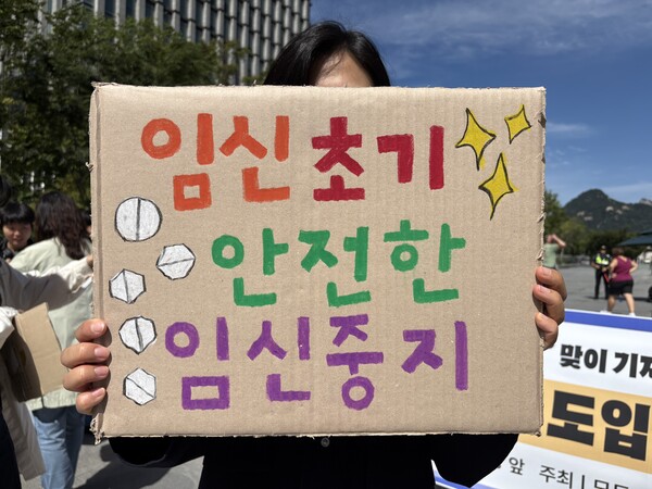 23일 서울 광화문광장 이순신 동상 앞에서 열린 '9.28 안전하고 합법적인 임신중지를 위한 국제 행동의 날' 맞이 기자회견에서 모두의 안전한 임신중지를 위한 권리보장네트워크 활동가가 '임신초기 안전한 임신중지'라고 적힌 피켓을 들고 있다. ⓒ신다인 기자