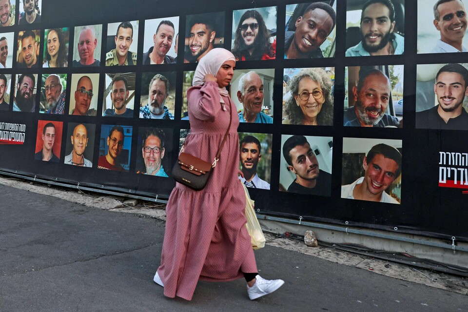 6일(현지시각) 예루살렘에서 한 여성이 2023년부터 팔레스타인 무장 세력에 의해 가자지구에서 인질로 잡혀 있는 이스라엘인의 초상화가 그려진 광고판을 지나가고 있다. ⓒAFP 연합뉴스