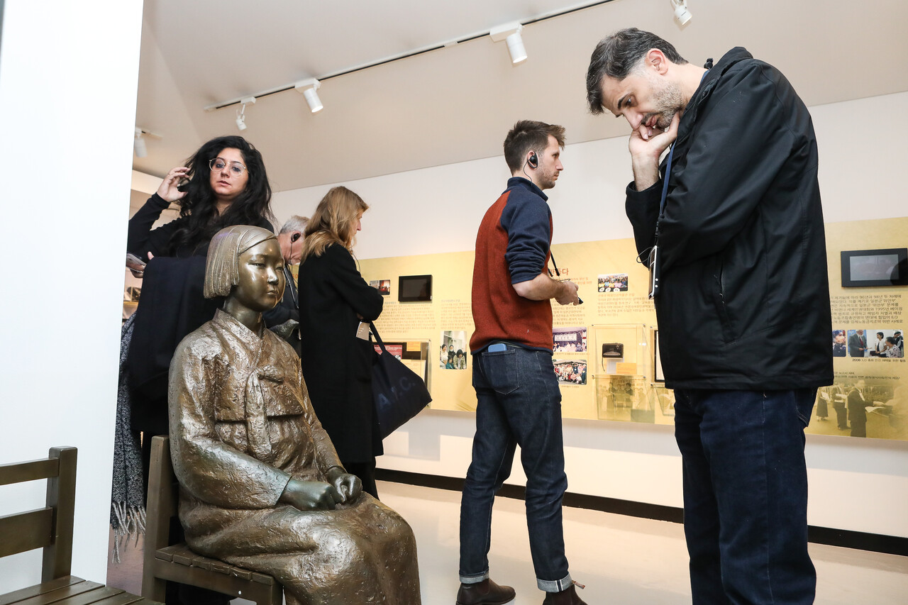 5일 서울 마포구 전쟁과여성인권박물관에서 2025 힌츠페터국제보도상 수상자들과 관계자들이 박물관을 관람하고 있다. 한 수상자가 소녀상 앞에서 생각에 잠겨 있다. ⓒ손상민 사진기자