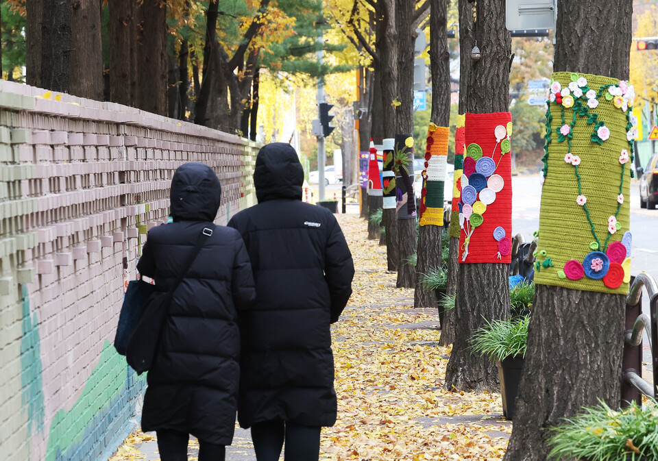 북쪽에서 찬 공기가 유입되며 추위가 찾아온 17일 경기도 광명시의 한 거리에서 두꺼운 옷차림의 시민들이 뜨개옷 입은 가로수길을 걷고 있다.  ⓒ연합뉴스