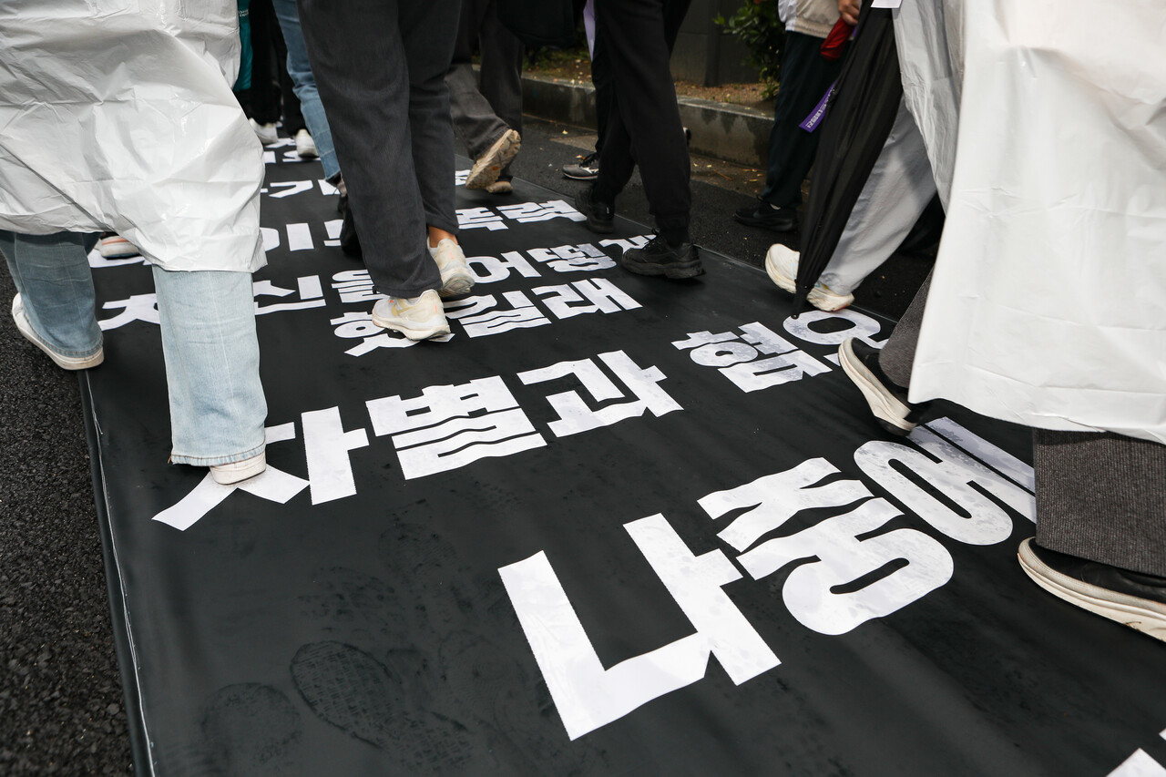 '윤석열 파면한 페미니스트 대행진'에서 참여자들이 여성혐오발언이 담긴 현수막을 밟고 지나가는 퍼포먼스를 하고 있다. ⓒ손상민 사진기자