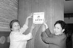 2006년 5월 여성재단 캠페인의 일환으로 요식업체 (주)놀부에서 ‘딸들에게 희망을 주는 가게 28호’로 약정을 한 후 놀부음식점 앞에서 김순진 사장(오른쪽)과 함께 현판을 달고 있는 모습.