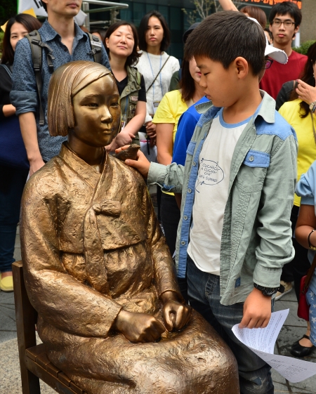 지난 9월 24일 오후 서울 종로구 주한일본대사관 앞에서 열린 일본군 위안부 문제 해결을 위한 제1145차 정기 수요시위에서 한 어린이가 위안부 소녀상을 살펴보고 있다.