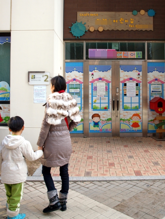 어린이집 원생 폭행 사건이 일어난 인천 연수구 송도동의 어린이집이 입구에 사과문을 내걸고 15일 임시 휴원했다. 휴원한 어린이집 앞에서 부모가 아이와 함께 서성이고 있다.