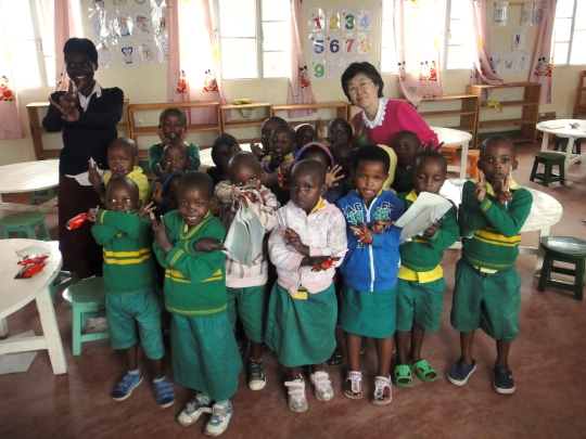 지난 6월 4일 르완다 새마을 운동 소학교를 방문한 이은재 한국행정연구원장이 아이들에게 한국에서 가져간 간식을 전달하고 기념촬영을 하고 있다.