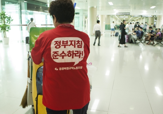 김포공항 용역 청소노동자가 정부지침 준수하라는 문구가 적힌 티셔츠를 입고 청소 업무를 하고 있다.