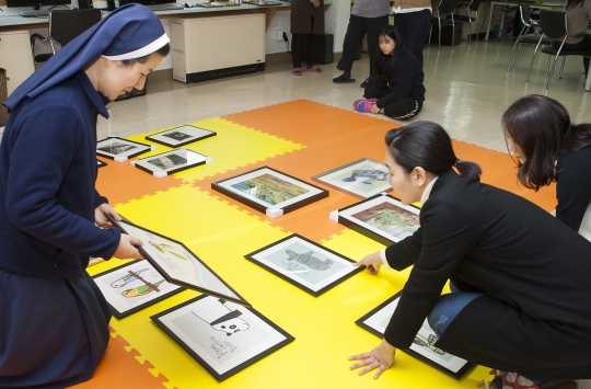 사랑의문화봉사단 봉사자들이 19일 서울 성북구 자오나학교를 방문해 미혼모들에게 그림을 걸어주는 전시봉사를 하고 있다. ⓒ이정실 사진기자