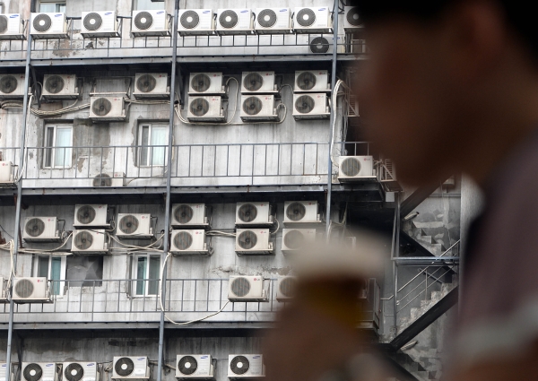 서울 시내 한 건물에 가득한 에어컨 실외기에서 더운 바람이 뿜어져 나오는 가운데 시원한 음료를 든 시민이 지나고 있다. ⓒ뉴시스·여성신문
