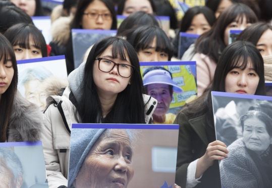 30일 오후 서울 종로구 중학동 (구)주한 일본대사관 앞에서 열린 일본군 위안부 문제해결을 위한 제1211차 정기 수요시위에 참석한 고등학생들이 올해 별세한 피해자 할머니들의 사진을 들고 있다.
