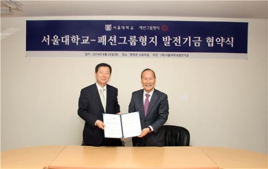 최병오 패션그룹형지 회장(오른쪽)이 26일 성낙인 서울대학교 총장에게 발전기금을 전달하고 있다.