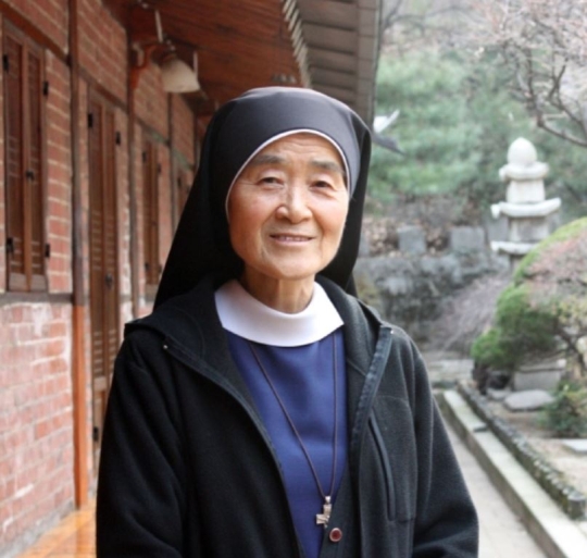 Clergywoman Okatarina smiling in the garden of the American Catholic Church of Korea located in Jung-gu, Seoul.