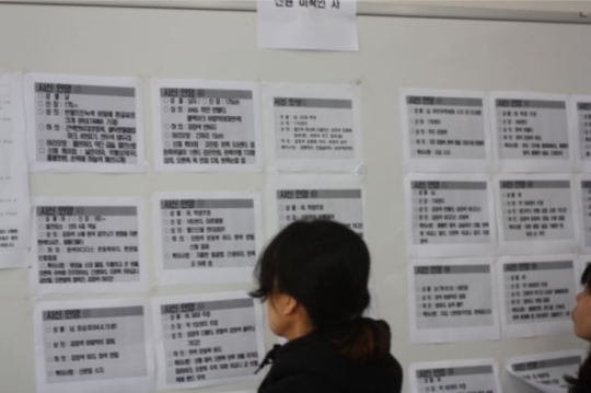 At the entrance of the gymnasium, a family member examines the list of unidentified bodies.