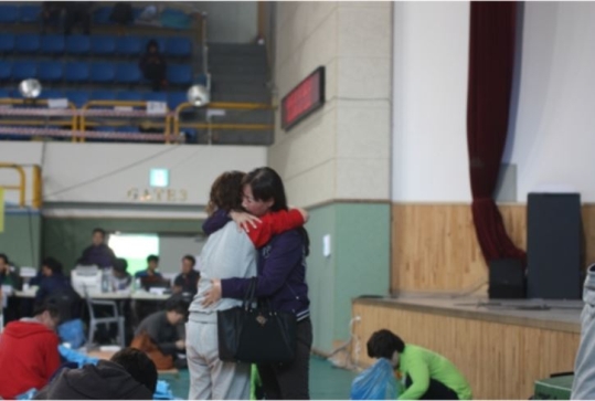 At a Jindo gymnasium, a family member of a missing passenger from the capsized ferry is being comforted by a friend.